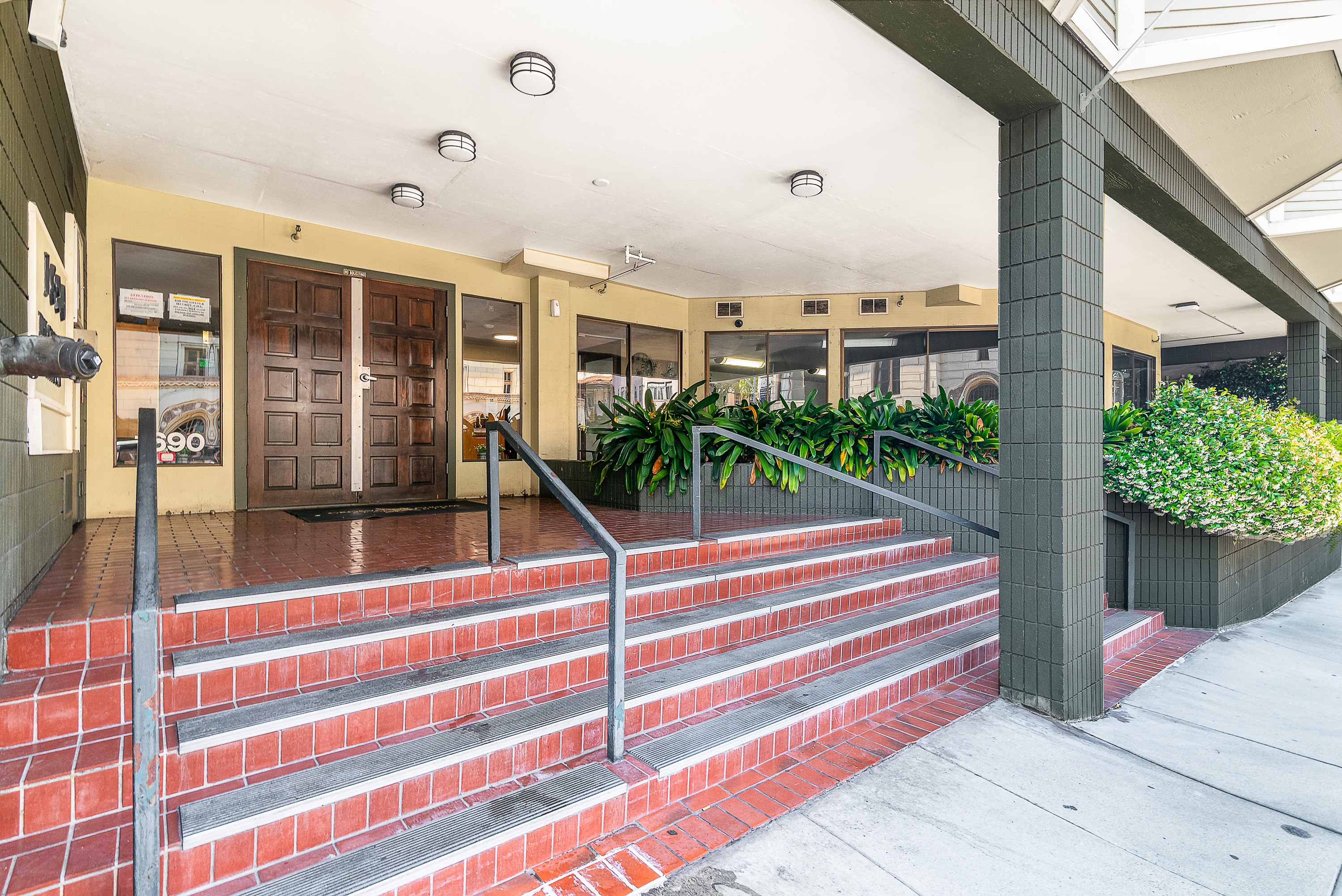 A set of stairs with red steps and a metal railing lead up to a building entrance.